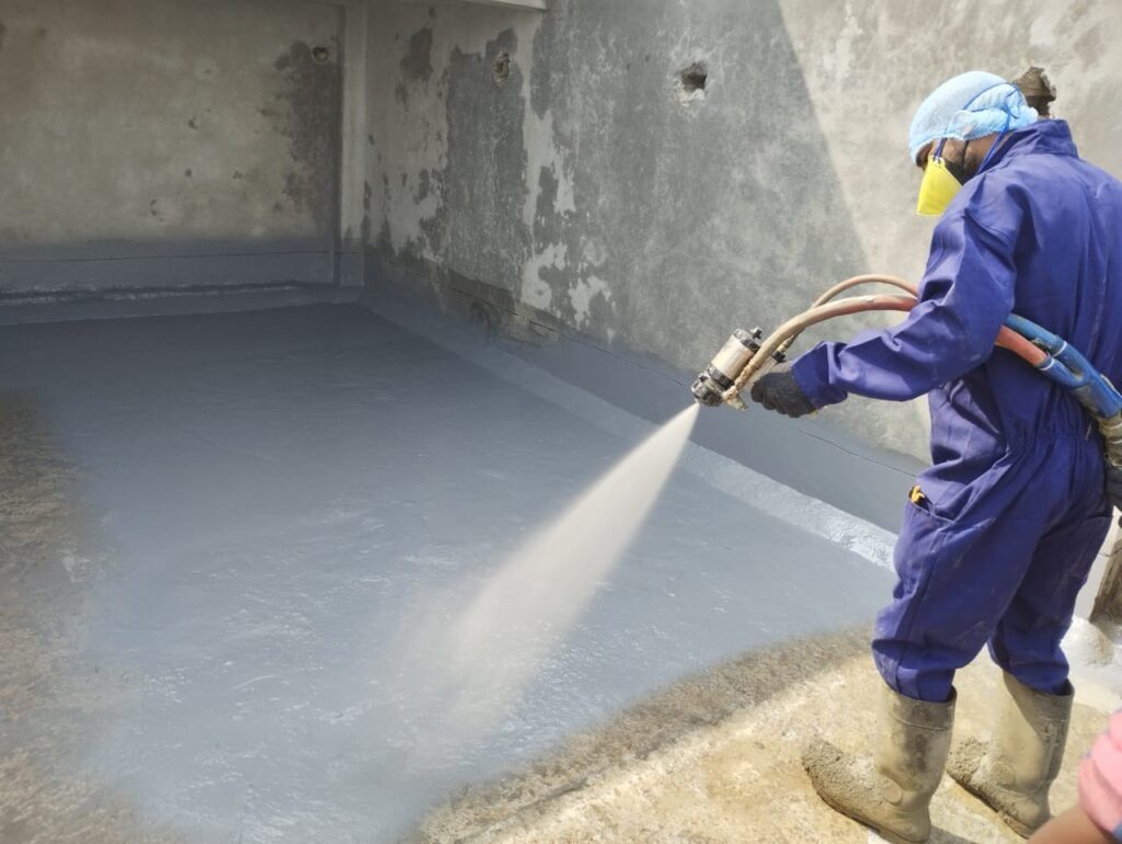 Applicator spraying polyurea on a basement floor